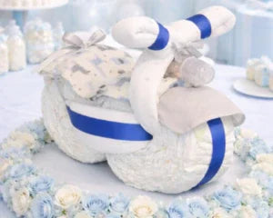 Handmade diaper cake shaped like a baby motorcycle with blue ribbons, perfect for baby shower gifts or keepsakes.